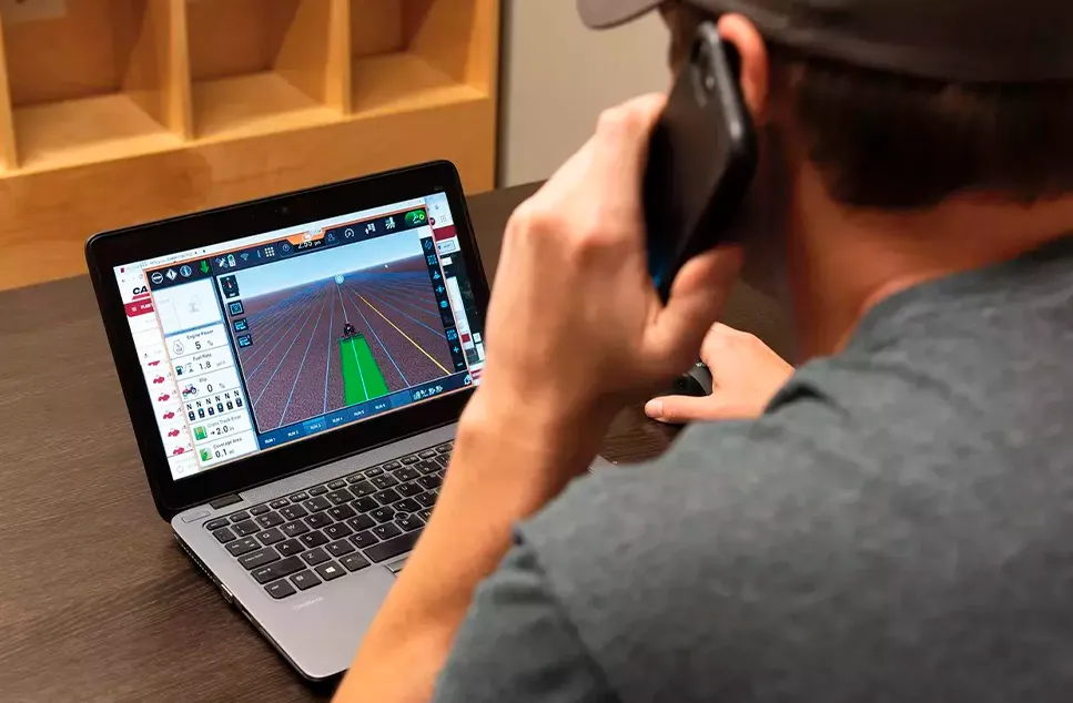 Hombre monitoreando ubicación de tractores en una computadora.