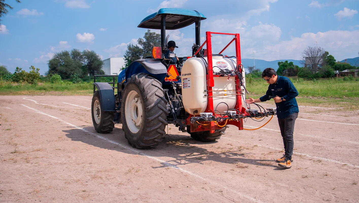 Un tractor equipado con el sistema de pulverización WeedSeeker 2, con un técnico inspeccionando los